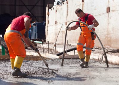 Arbeiter gießen Beton auf Baustelle.
