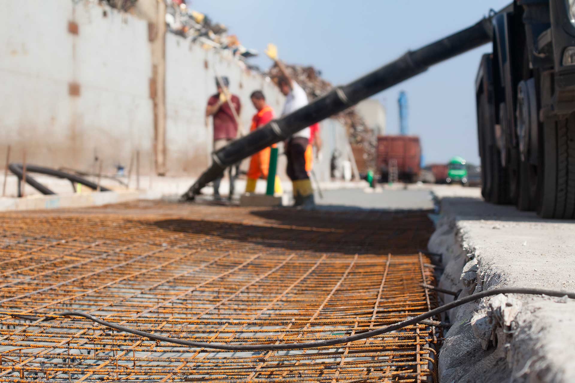 WHITETOPPING/DBA  (DÜNNE BETONSCHICHT AUF ASPHALT): Arbeiter gießen Beton auf Stahlmatten