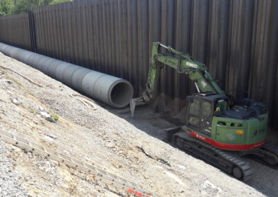 Bagger arbeitet an Rohrverlegung.