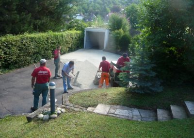 Arbeiter verlegen Kies auf Auffahrt.