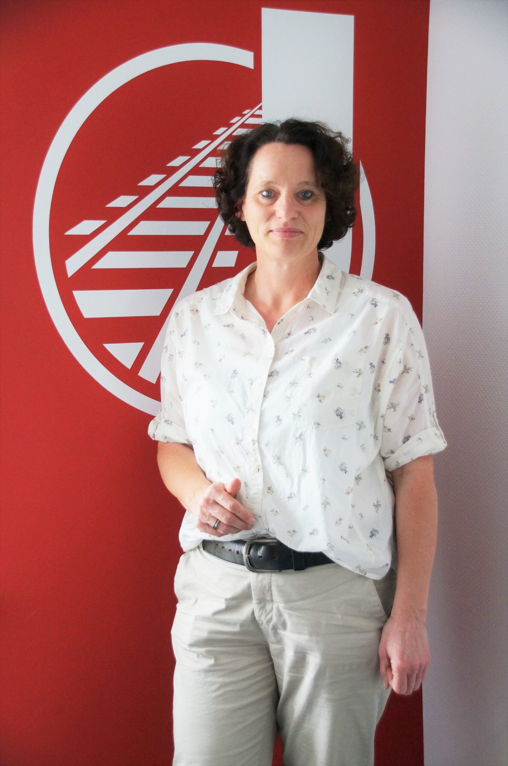 Andrea Springer: Büromanagement. Frau vor rotem Hintergrund mit Jörger Logo
